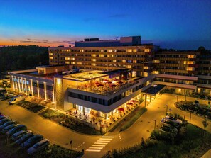 A multi-story hotel with outdoor seating, a parking lot, and a pedestrian crossing. - Arche Nałęczów Dawne Sanatorium (Naleczow)