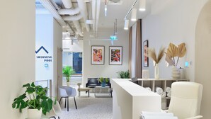 A modern hotel lobby with a reception desk, seating area, and a sign for the swimming pool.
