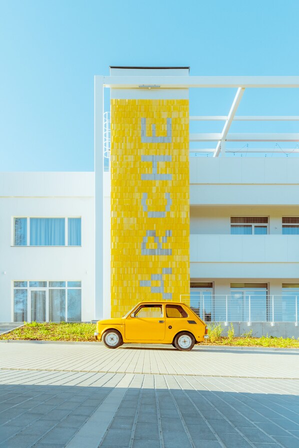 A yellow car parked in front of a building with a yellow vertical panel. - Arche Nałęczów Dawne Sanatorium (Naleczow)