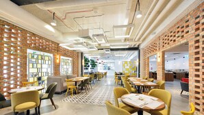 A modern interior with brick walls, yellow chairs, and tables arranged in a spacious dining area.