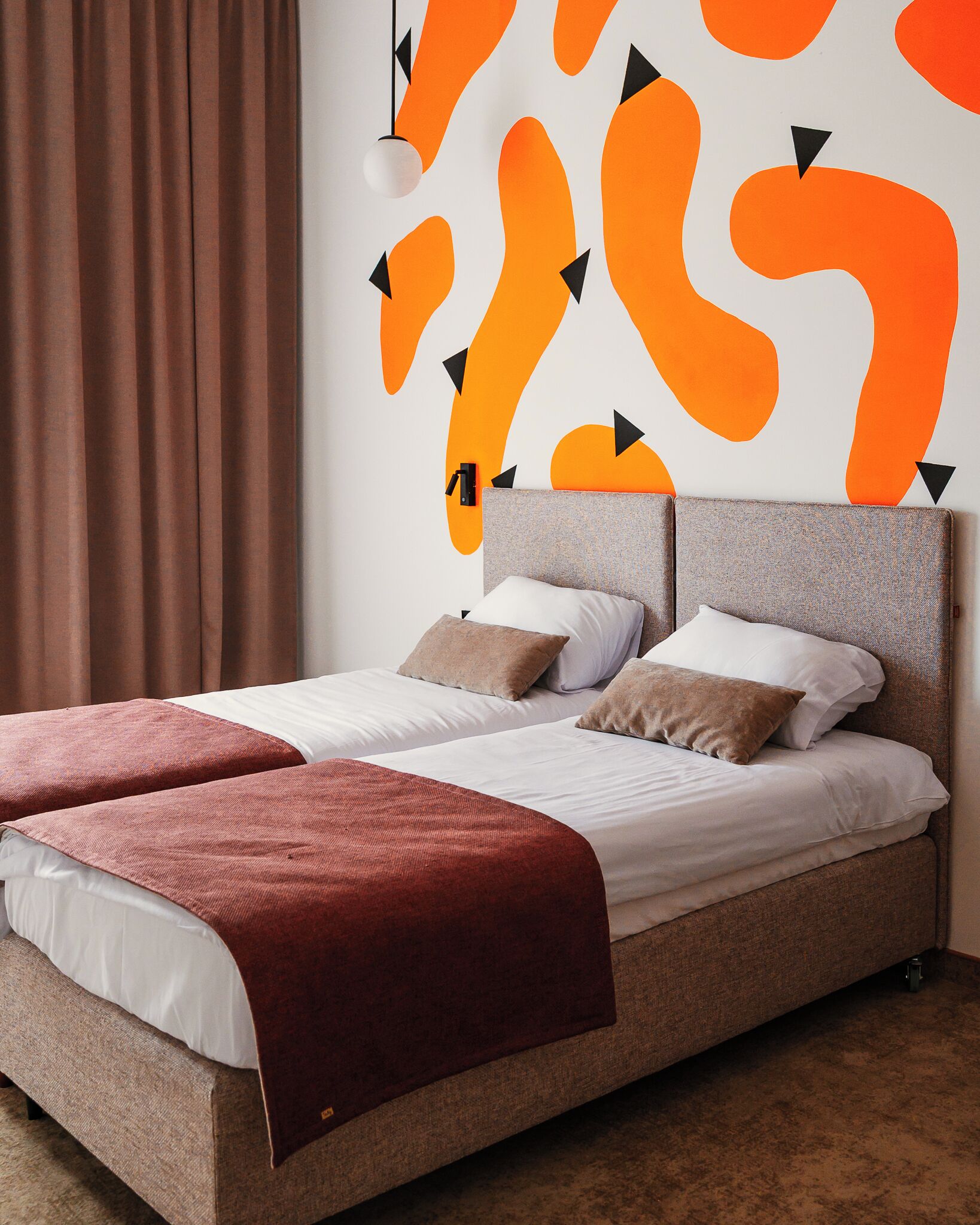 A double bed with a headboard, two pillows, and a red blanket.