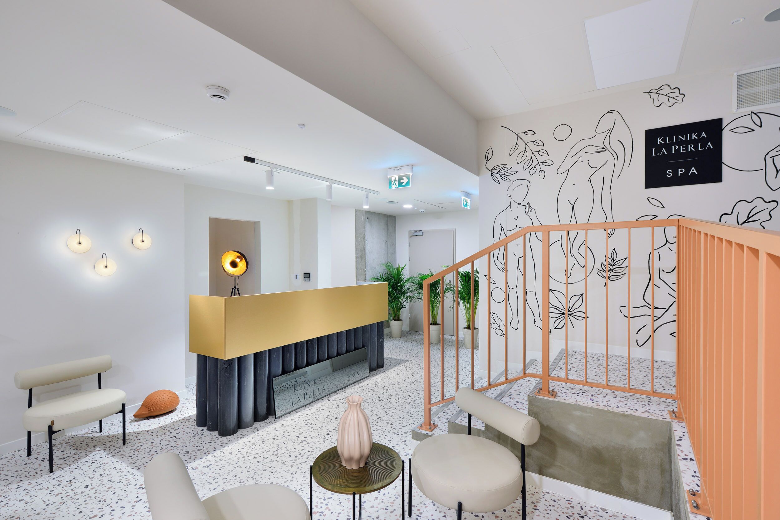 A modern reception area with a counter, seating, and a staircase.