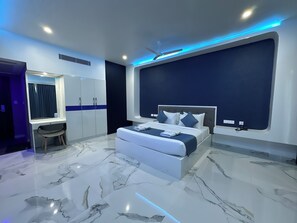 Quarto moderno com uma cama grande, uma penteadeira com espelho e uma escrivaninha.