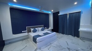 A modern bedroom with a large bed, a ceiling fan, and a dark blue accent wall. - Silver Stone Park Resort (Nagpur)