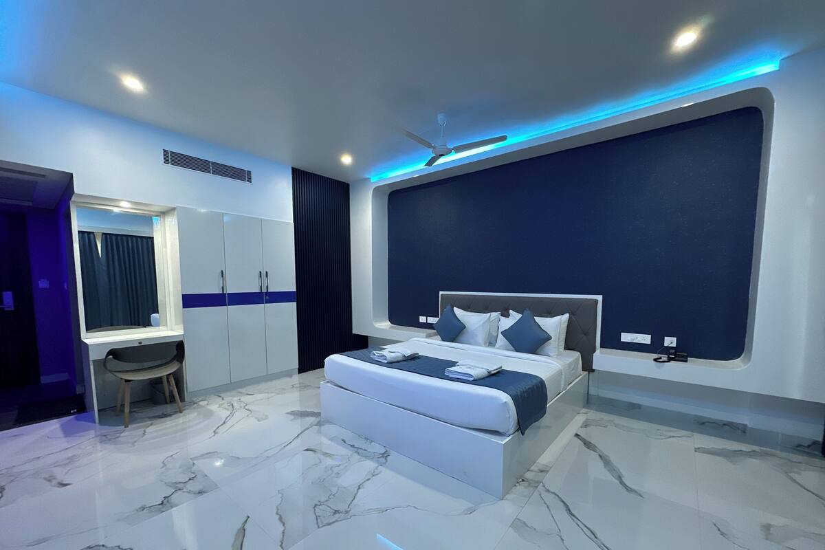 Une chambre moderne avec un grand lit, une coiffeuse avec un miroir et un bureau.