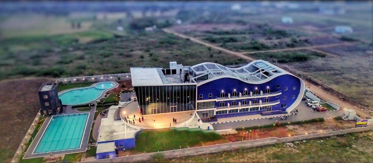 A modern building with a curved roof, a swimming pool, and a large glass facade.