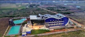 A modern building with a curved roof, a swimming pool, and a large glass facade. - Silver Stone Park Resort (Nagpur)