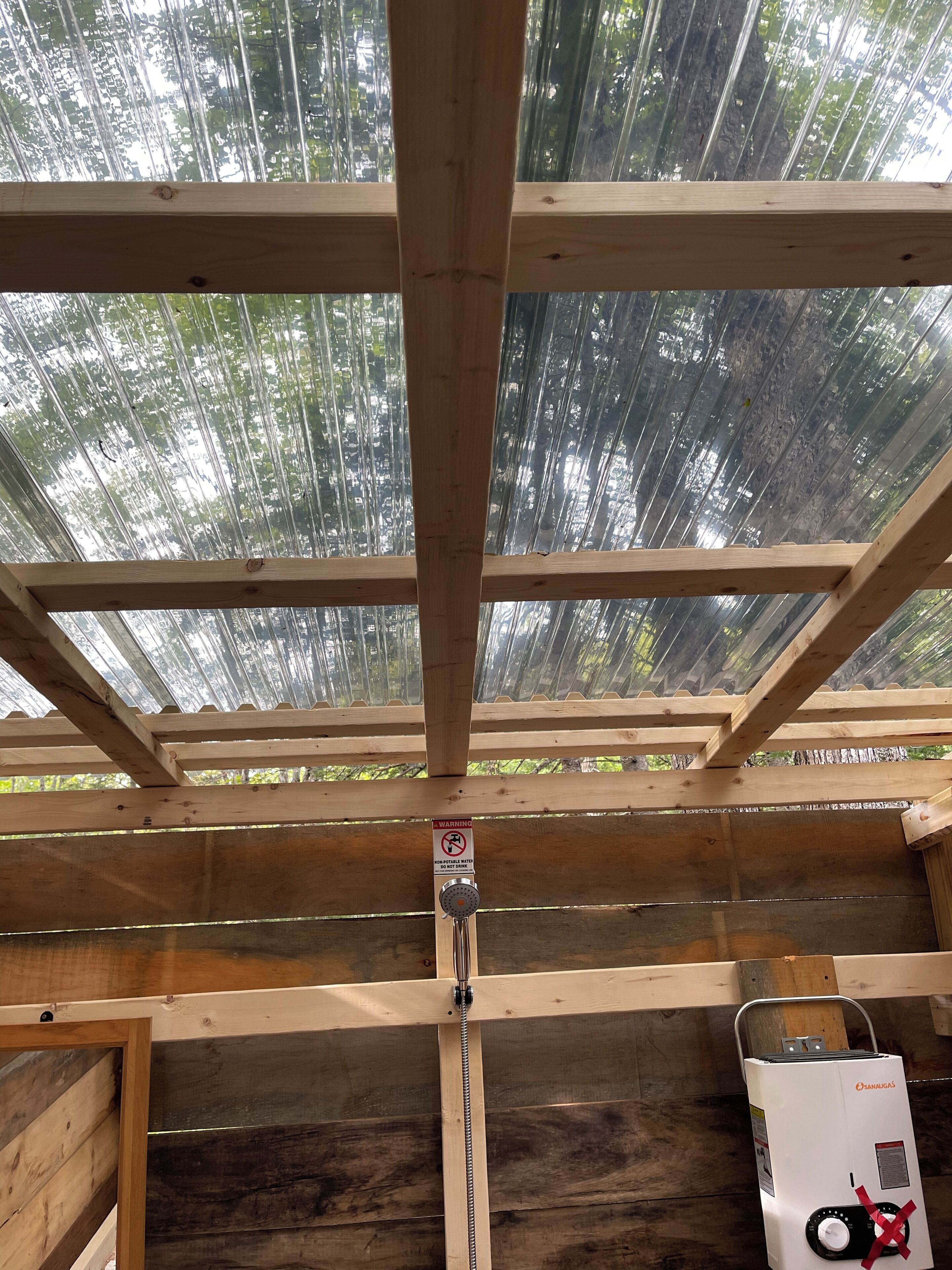 Une structure en bois au plafond, avec un chauffe-eau et un panneau d’avertissement.