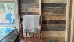 Ein rustikales Holzinterieur mit einem Holzstuhl, einem kleinen Topfpflanzen und einem Spiegel an der Wand.