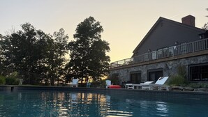 Ein Schwimmbecken mit Liegestühlen und ein Gebäude mit Steinbau und einem Balkon.