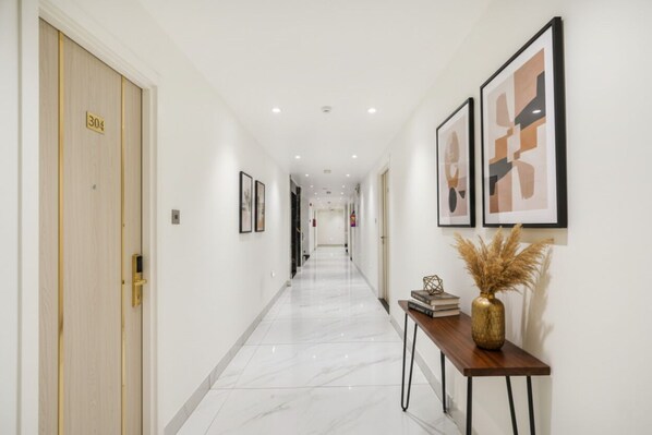 A hotel hallway with a marble floor, a wooden door labeled '304', and framed artwork on the walls. - Fabhotel Luxury Inn Adarsh Nagar (New Delhi)