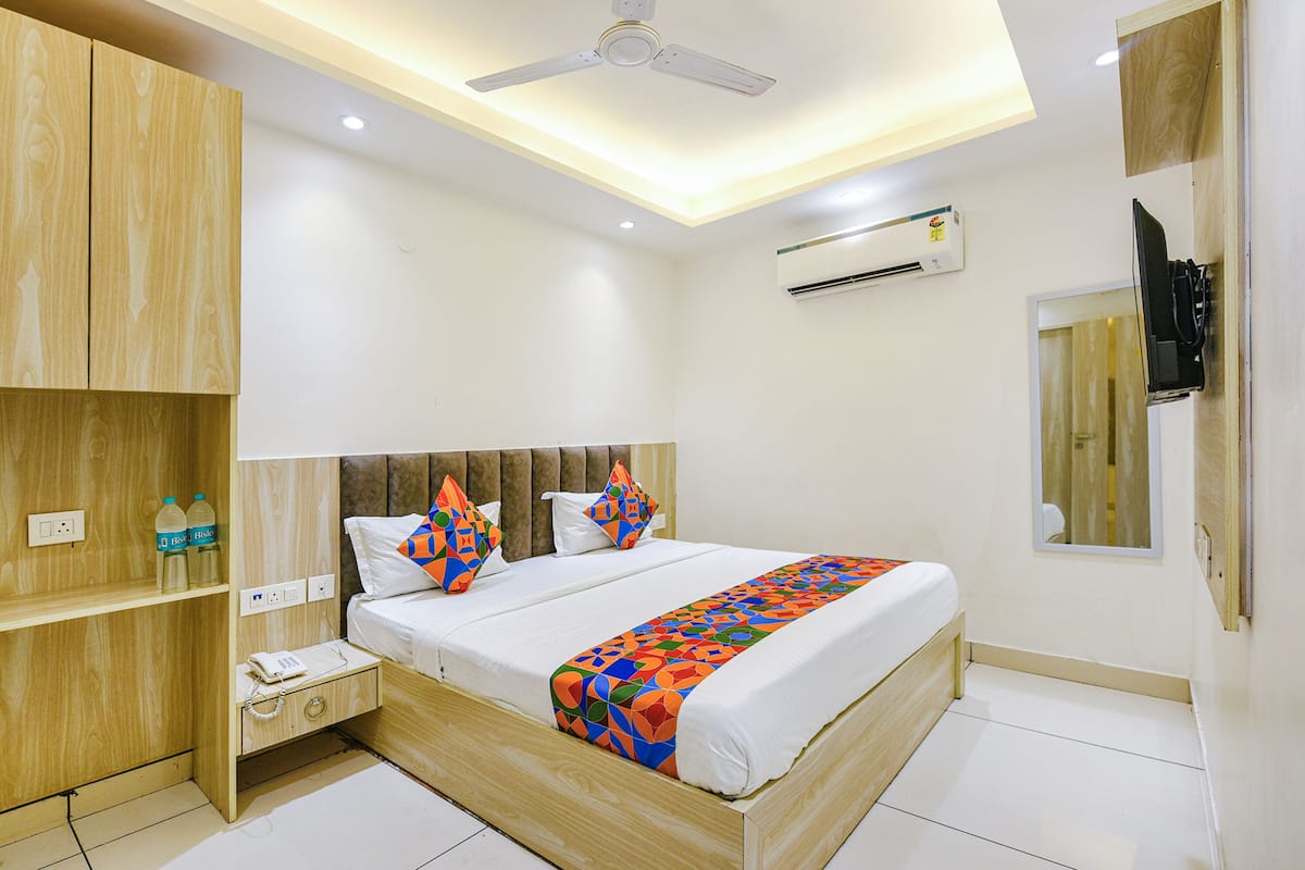A hotel room with a wooden bed frame, a bedside table with a phone, and a ceiling fan.