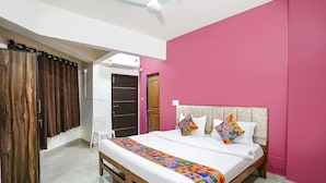 A bedroom with a bed, a ceiling fan, a wardrobe, and a door. - Via Sunset Residency (Navi Mumbai)