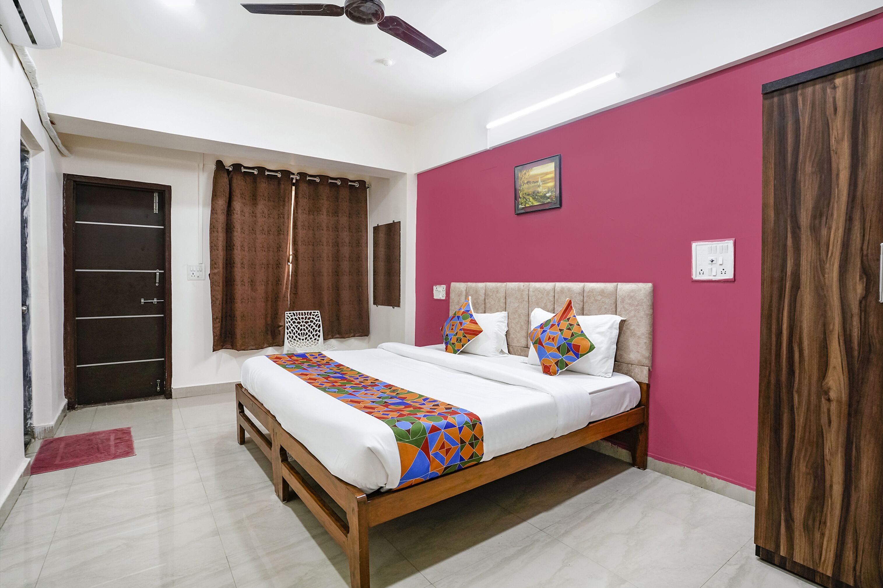 A bedroom with a bed, curtains, a ceiling fan, and a wooden wardrobe.