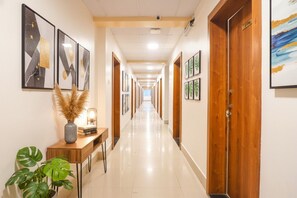 Un corridoio d'hotel con opere d'arte appese alle pareti, una reception in legno e una pianta in vaso.