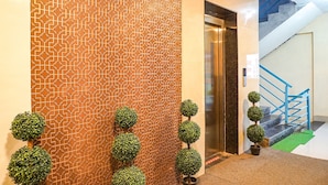 A lobby with a patterned wall, an elevator, and a staircase with blue railings. - FabHotel Embassy (Pune)