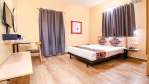 A bedroom with a bed, a desk, a chair, and a small table. - Fabhotel Saltel (Kolkata)
