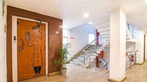 A hotel lobby with a wooden door, a staircase, and a potted plant. - Fabhotel Saltel (Kolkata)