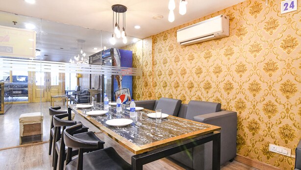 Un espace repas comprenant une longue table, des chaises et un lustre moderne.