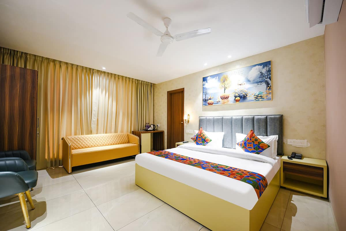 A hotel room with a bed, a sofa, a desk, and a ceiling fan.
