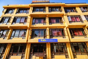 Um hotel de vários andares com fachada amarela, várias janelas e uma placa com a inscrição 'Tab Hotels'.