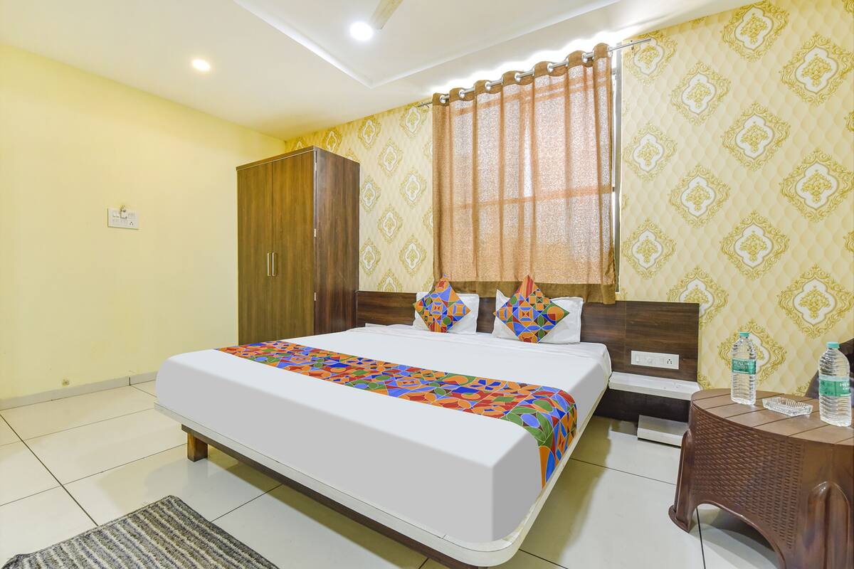 A hotel room with a large bed, a wardrobe, a nightstand, and a bathroom.