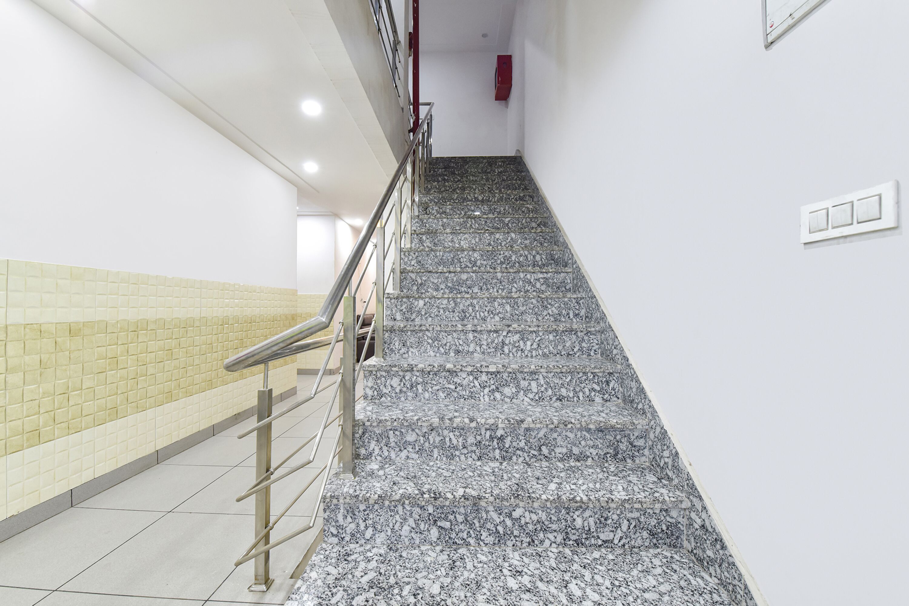 A staircase with a metal handrail and tiled walls.