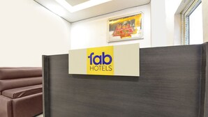 A reception area with a 'fab hotels' sign, a brown sofa, and a framed picture on the wall. - Fabexpress Perfect (Samba)
