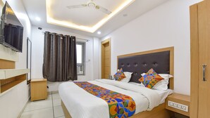 A modern hotel room with a large bed, a TV mounted on the wall, and a ceiling fan. - Fabexpress Perfect (Samba)