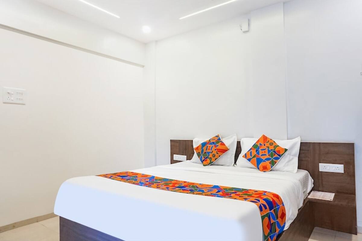 Habitación de hotel con cama, mesita de noche y enchufe.
