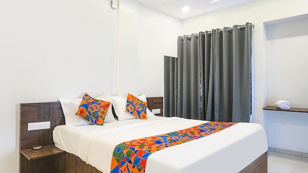 Una camera d'albergo moderna con un letto grande, un comodino e una tenda.