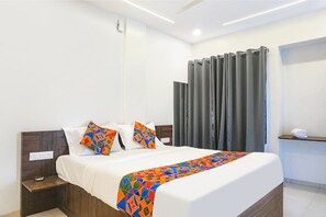 A modern hotel room with a large bed, a nightstand, a bedside table, and a curtain. - Fabhotel Sadanand Executive (Pune)