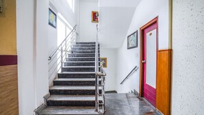 Eine Treppe mit Metallgeländern, einer Holzhandläufe und einer roten Tür am unteren Ende.