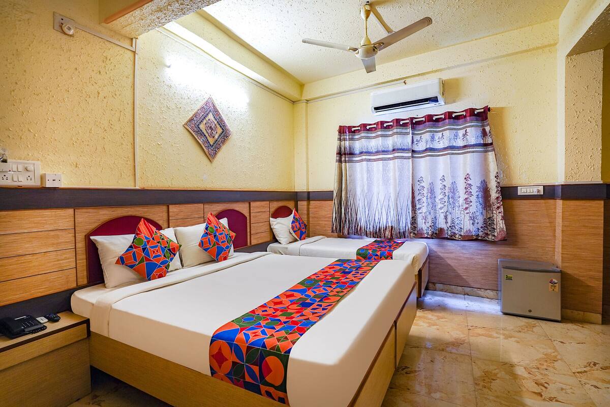 Une chambre d’hôtel avec deux lits, un petit réfrigérateur, un appareil de climatisation et une fenêtre avec des rideaux.