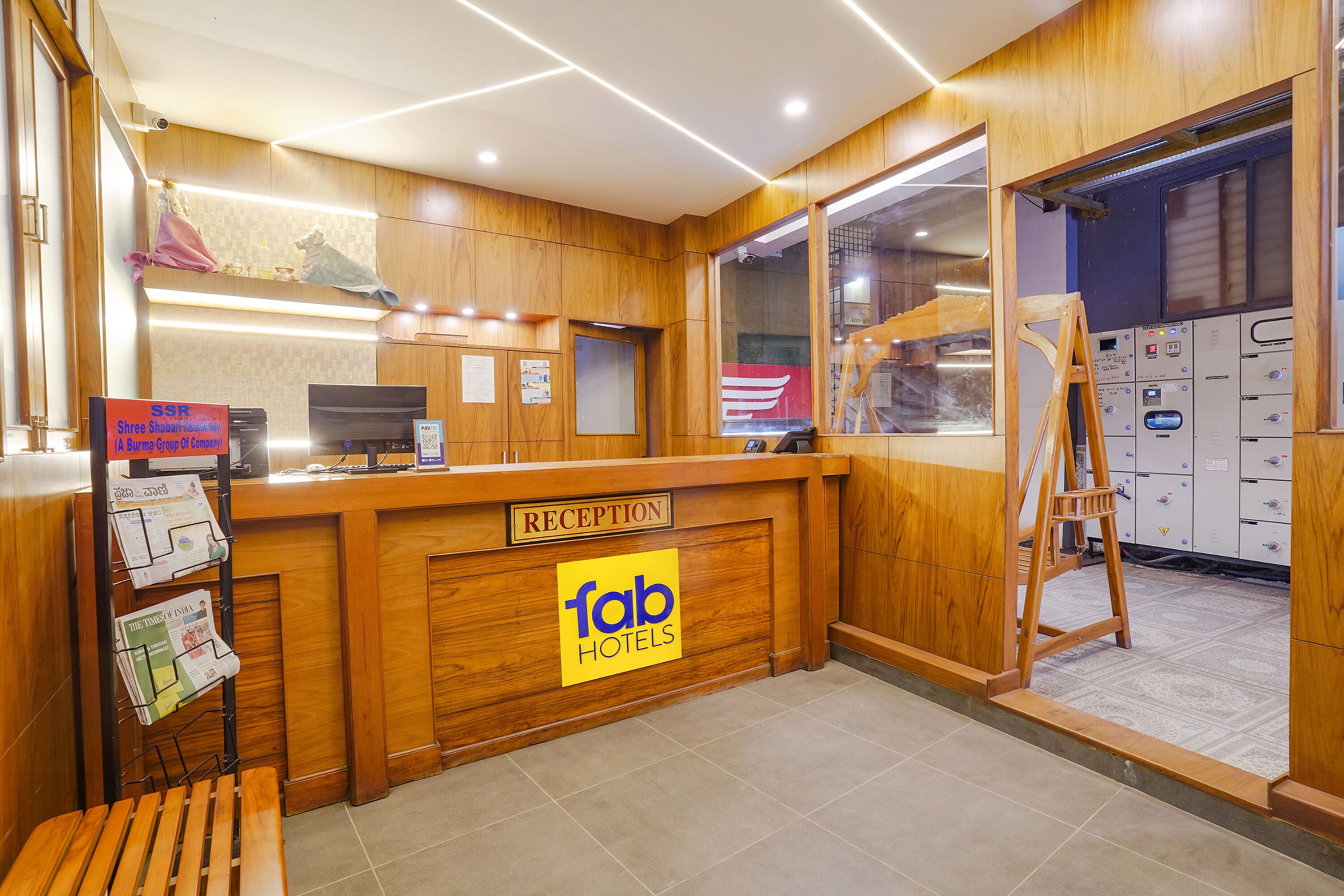 A reception desk with a wooden finish, a sign for 'fab hotels', and a bench to the left.