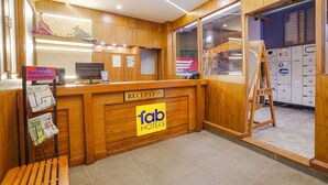 Ein Empfangsschalter mit Holzausstattung, ein Schild mit der Aufschrift 'fab hotels' und eine Bank links.