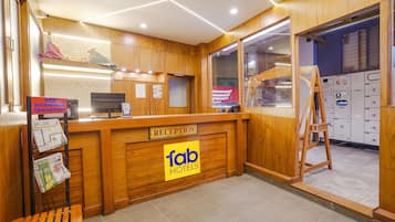 A reception desk with a wooden finish, a sign for 'fab hotels', and a bench to the left.