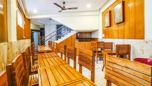 Ein Restaurant mit Holztischen und -stühlen, einem Deckenventilator und gerahmten Bildern an der Wand.