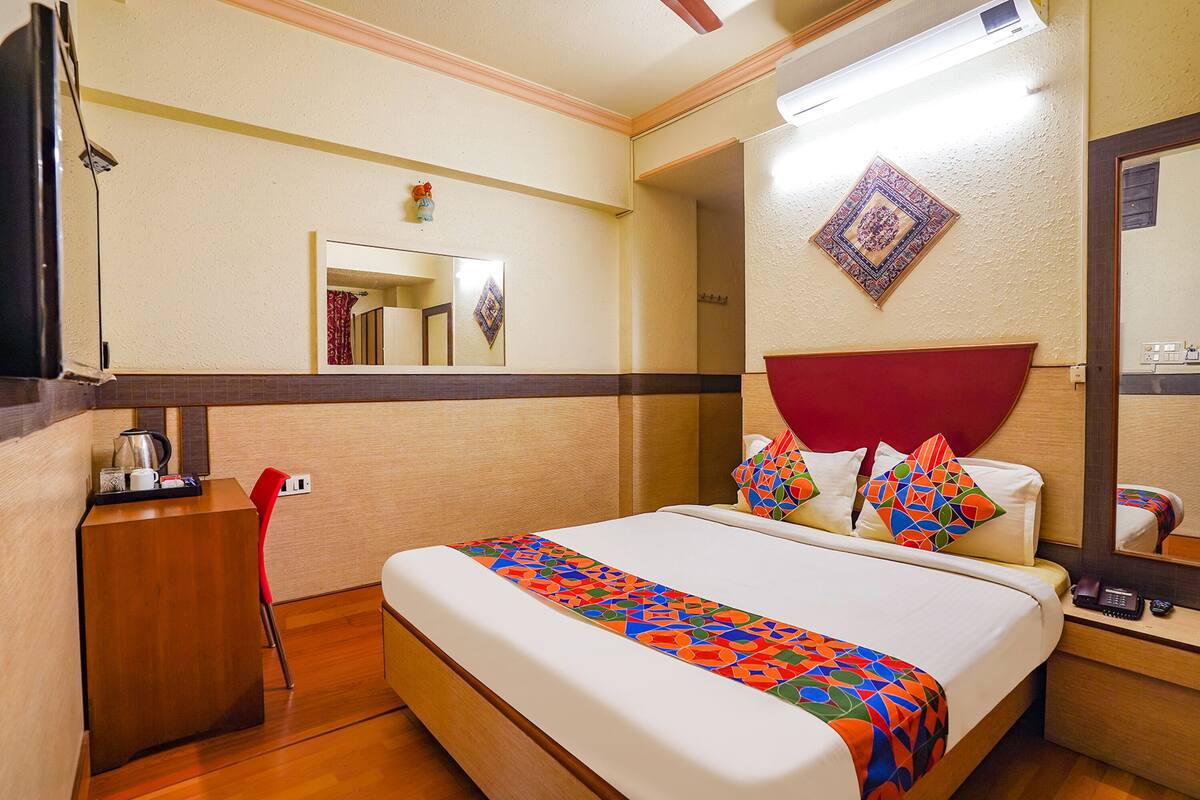 Une chambre d’hôtel équipée d’un lit, d’un bureau, d’une chaise, d’un téléphone et d’un miroir.
