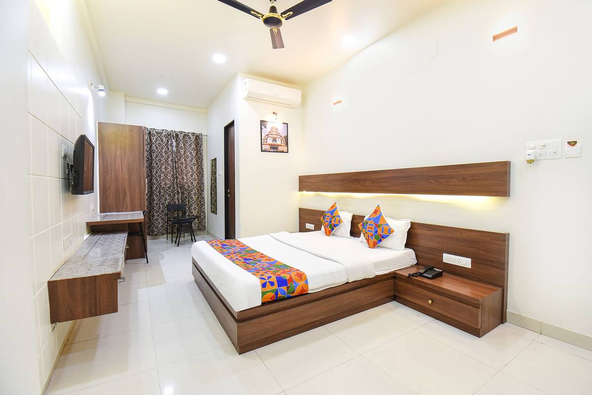 A bedroom with a bed, bedside tables, a desk, a chair, and a ceiling fan.