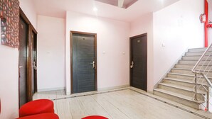 A hotel lobby with a staircase, two doors, and red seating. - Fabhotel Gayatri Inn Annex (Nagpur)