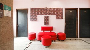 A reception area with a red sofa set, a large abstract artwork, and three doors labeled 205, 204, and 203. - Fabhotel Gayatri Inn Annex (Nagpur)