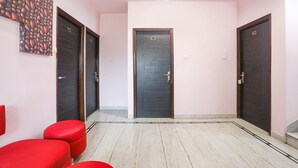 A hallway with three doors, numbered 201, 202, and 211, and a red bench on the left. - Fabhotel Gayatri Inn Annex (Nagpur)