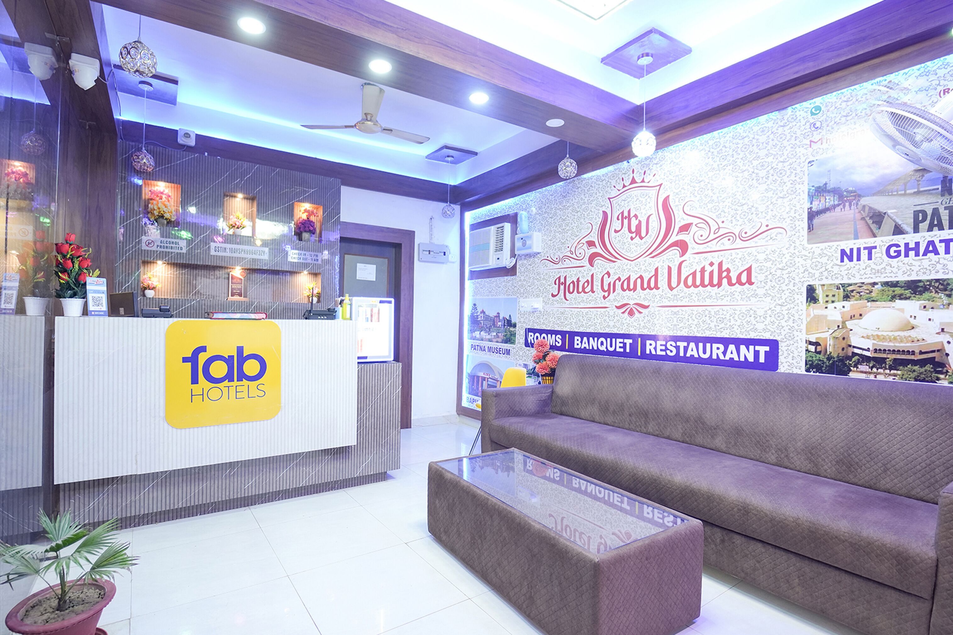 A hotel reception area with a reception desk, a sofa, and a potted plant.