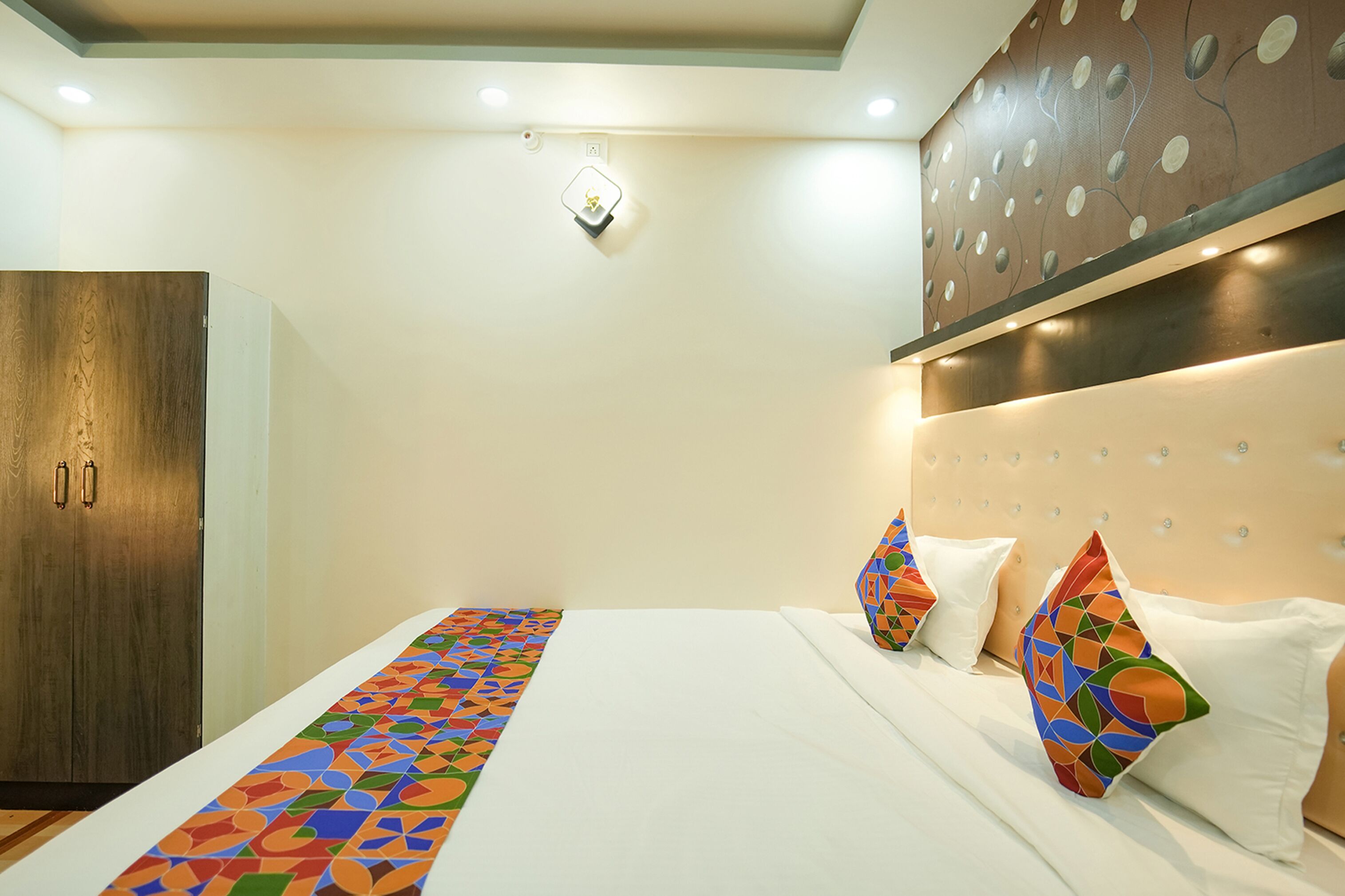 A hotel room with a bed, a wardrobe, and a decorative wall panel.