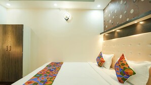 A hotel room with a bed, a wardrobe, and a decorative wall panel. - Fabhotel Grand Vatika (Danapur)