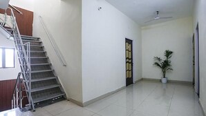 Un pasillo amplio con escaleras, un ventilador de techo y una planta en maceta.