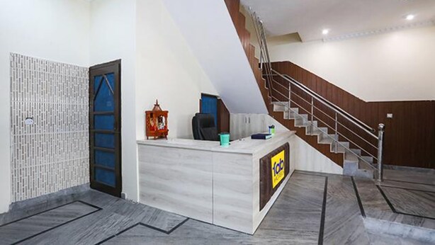 Zona de recepción con mostrador, escalera y puerta con marco azul.