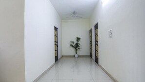Un pasillo con ventilador de techo, planta en maceta y puertas con diseños decorativos.