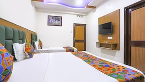 A hotel room with a large bed, a television mounted on the wall, and a door with a wooden panel. - Fabhotel Arjun (Nagpur)